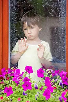 Gloomy Prints: Little boy behind the window in the rain, looking sad