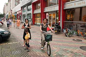 Dongguan Prints: Little Chinese boy peeing on a pavement with his mother waiting for him and people passing by