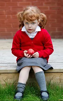 Skirt Prints: Little girl, age 4, wearing her school uniform in a garden