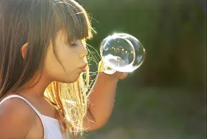 Pigtail Prints: little girl blowing soap bubbles at sunset