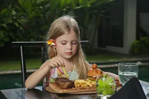 Fastfood Prints: Little girl eating french fries with tomato sauce at the restaurant