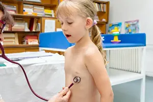Little girl is having systematic examination with stethoscope in doctor's office