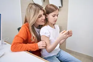 Thermometer Prints: Little girl sitting on mother's knee in doctor office and looking at thermometer