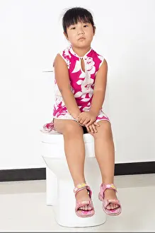 The little girl sitting on the toilet