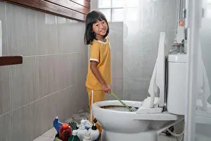 Odor Prints: The little girl smiles at the camera while using the toilet brush to clean the dirty toilet