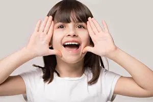 Little girl call somebody holding hands near face studio shot
