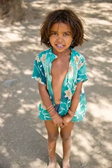 A little girl stands in the shade of a tree in a small village near the Ajanta Caves, India