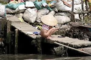 Little girl using the river dock as a toilet, Mekong Delta, Vietnam