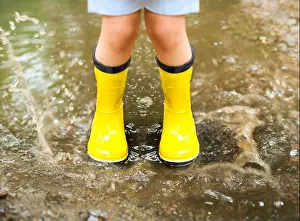 Messy Prints: Little girl wearing yellow boots and coat jumping in rainy day