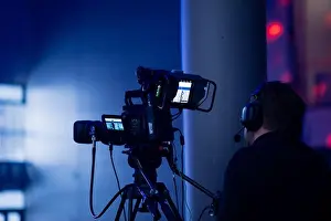 Headset Prints: Live event videographer operating a broadcast camera system with tripod