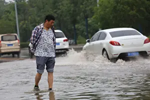 Flooding Prints: A local resident searches for missing car license plate on a flooded road in Xiangyang city