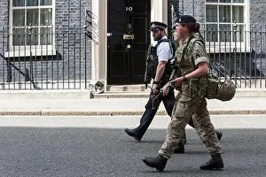 Guarding Prints: London, UK. 24 May 2017. A police officer and two female soldiers walk past the front door of No