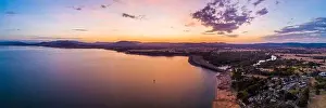 Lonely boat sailing across scenic lake at vivid orange sunset - aerial panoramic landscape