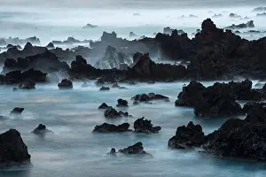 Long exposure of surf pouring over lava rocks at Easter Island; Easter island, Chile