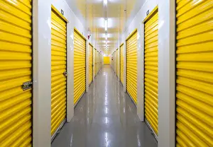 Expansive Prints: A long hallway containing many storage units inside a self storage building