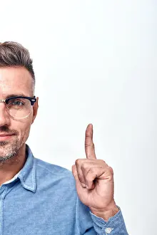 Glance Prints: Look here Half face portrait of a smiling man with a stubble in eyewear gesturing and looking at camera