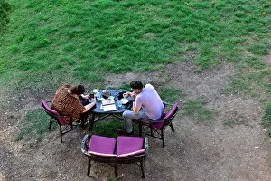 Rovinj Prints: Looking from above at two people eating outside in park at table