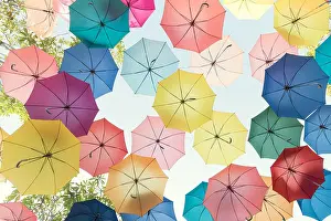 Parasol Prints: Lots of colorful umbrellas flying in sky over city street during summer festival