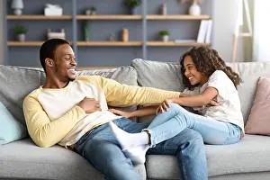 Embracing Prints: Loving black father and daughter tickling each other