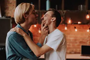 Cuddling Prints: Loving gay couple at home. Two handsome men hugging and kissing on kitchen. LGBT concept