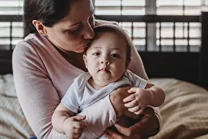 Generation X Prints: Loving mid-30â€™s mom cuddling baby girl on lap in bedroom near window