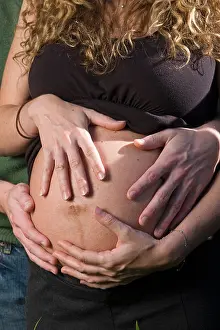 Adoring Prints: In a loving moment a pregnant woman and her husband touch her belly