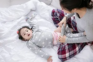 Pajamas Prints: Loving mother taking care of daughter in multicultural family