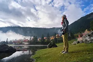 Sichuan Prints: Low angle full body of calm Asian Woman with professional photo camera standing on grassy coast of lake against Tibetan