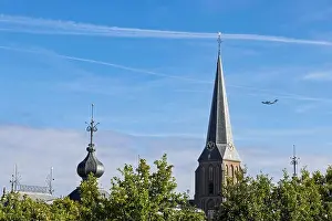 Airborne Prints: A low-angle shot of a historic church spire in Arnhem with an airplane flying past