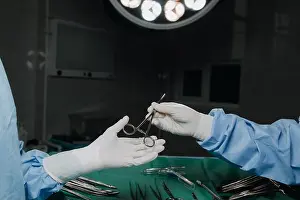 Urgency Prints: Low angle shot in operating room, assistant hands out tools to surgeons during surgery