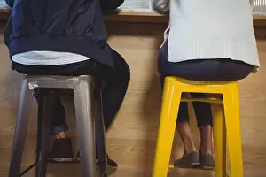 Young Couple Prints: Low section of couple sitting on stools