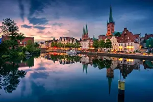 Lubeck, Germany. Cityscape image of riverside Lubeck with reflection of the city in Trave River at sunset