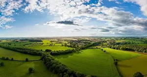 Lush green fields with hedgerows stretch across the landscape under a partly cloudy sky in North Yorkshire