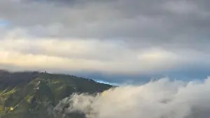 Low Clouds Prints: Lush green mountain in Tenerife partially covered by low clouds with a moody sky overhead