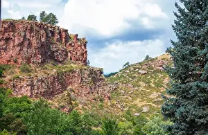 Red Rock Prints: Lush greenery surrounds dramatic red rock formations under a vibrant cloudy sky in the mountains of Colorado USA