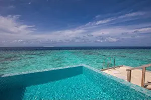 Beach Landscape Prints: Luxurious beach resort with swimming pool and beach chairs or loungers under umbrellas with palm trees and blue sky
