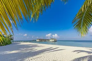 Luxury hotel with water villas and palm tree leaves over white sand close to blue sea seascape. Tranquil paradise landscape, seaside sunny destination