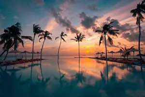 Luxury resort beach. Beautiful poolside and sunset sky. Luxurious tropical beach landscape, deck chairs and loungers infinity pool water reflection
