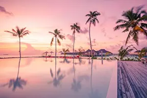 Luxury resort beach. Beautiful poolside and sunset sky. Luxurious tropical beach landscape, deck chairs and loungers infinity pool water reflection