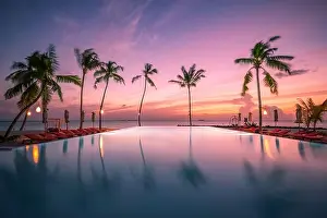 Luxury resort beach. Beautiful poolside and sunset sky. Luxurious tropical beach landscape, deck chairs and loungers infinity pool water reflection