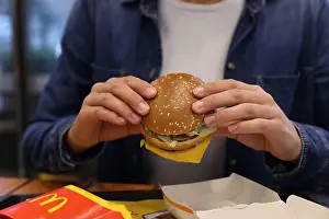 Mcdonald Prints: Lviv, Ukraine - October 9, 2023: Woman with McDonald's burger at table in restaurant