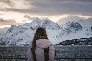 Lyngen Alps mountains at sunset behind woman on boat in arctic Norway