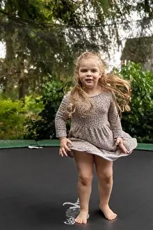 Lynwood, Washington, USA. 4 year old girl bouncing on her trampoline. (MR)