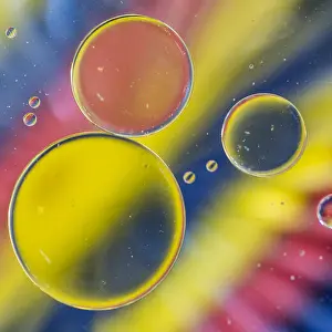 Separation Prints: A macro shot of oil floating on water above a colourful background of coloured pencils