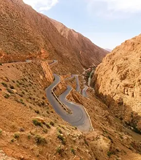 From above of majestic landscape of narrow winding roadway going between rough rocks against blue sky