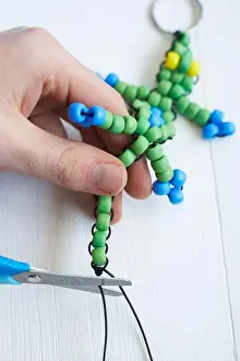 Cord Prints: Making beaded lizard key ring, cutting off excess string with scissors