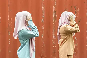 Malaysian Prints: Two malaysian young lady in modern attire reacting happily with authentic malaysian smile at outdoor location