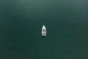 Lake Garda Prints: Malcesine, Italy - August 7, 2019: Aerial drone shot view of two men in a white boat in lake garda