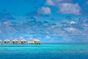 Maldives island, luxury water villas resort and wooden pier. Beautiful sky and clouds and beach background for summer vacation holiday and travel