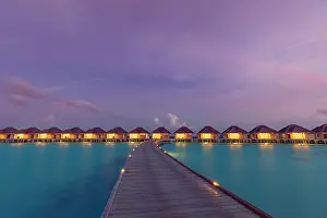 Maldives island sunset. Water bungalows resort at islands beach. Indian Ocean, Maldives. Beautiful sunset landscape, luxury resort and colorful sky